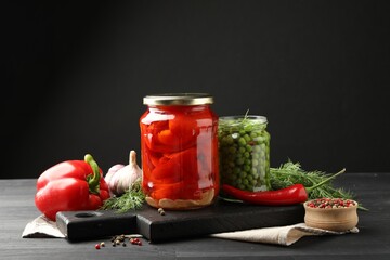 Different pickled products in jars and fresh ingredients on grey wooden table
