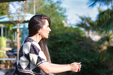 Beautiful young Latin woman leaning on the iron railing is sad and depressed looking across the...