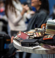 Close up of  makeup with a make up artist diffused in the background