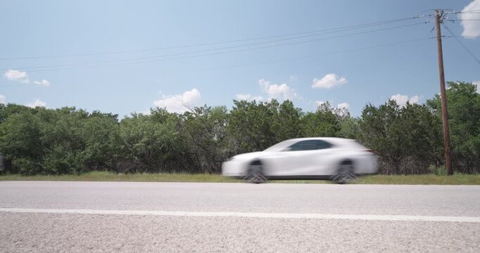 Trucks, cars, and SUVs drive along highway 290 outside Johnson City, Texas in the Hill Country - slider right to left