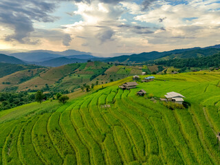 Landscape of green rice terraces and traditional huts in a village near Chiangmai, Thailand. Travel destinations. Beauty of terraced rice fields. Rural life and traditional farming practices in Asia.