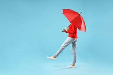 Woman with red umbrella walking on light blue background, space for text