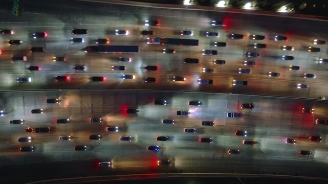 An aerial photo captures a bustling night traffic jam in Downtown LA, depicting cars trapped in a gridlock on a busy highway, showcasing the challenges of commuting in a metropolitan city