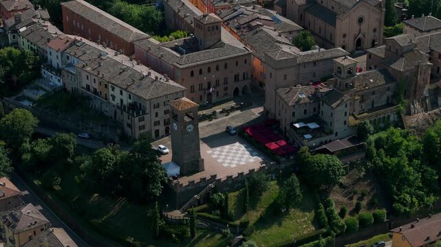 Aerial view of the clock tower and historic courtyard in Castelvetro di Modena, Italy. The scene captures the charm of the Italian comune.