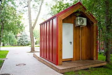This modern, contemporary tiny house beautifully combines wooden and metal design elements, elegantly set amidst vibrant greenery in a tranquil, peaceful park setting