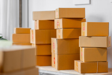 Parcel boxes on shelf and color shopping bags placing near laptop on table. SME business on shopping online at home office packaging on background is popular business.
