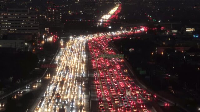 In downtown Los Angeles, California, a clear 4K view captures a noticeable traffic jam crossing lanes in each direction during the night, depicting a bustling cityscape filled with moving vehicles