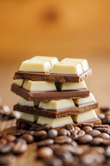 White light dark chocolate bars and coffee beans on wooden table.