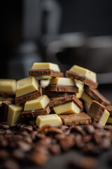 White light dark chocolate bars and coffee beans on black table.