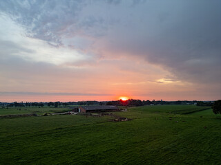 Obraz premium A stunningly beautiful sunset with warm and vibrant hues gracefully casting light over a peaceful countryside field