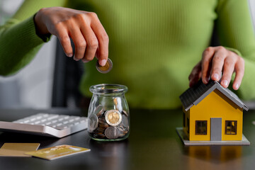 saving money, Real estate concept background. Hand of House model and coins stack on wooden table, Business and tax concept copy space.