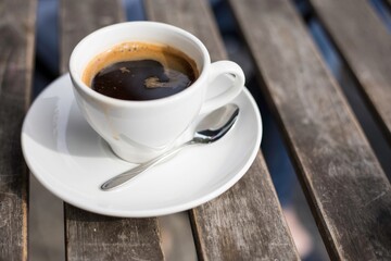 Obraz premium Looping 4K image of Hot Espresso with Steam Rising on a Wooden Table, Capturing the Rich Aroma and Visual Delight of Freshly Brewed Coffee 