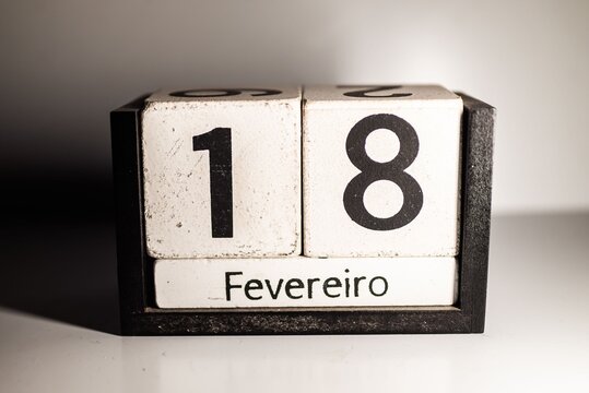 Close-up of a wooden calendar showing the date 18th of February in Portuguese.