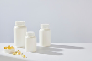 High angle shot at white background photo, some white supplement jars without label, featured on the left side, blank right side for product advertising. Copy space, designing template