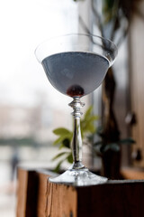 delicious cool cocktail in beautiful glassware on a wooden table in a cozy nice restaurant