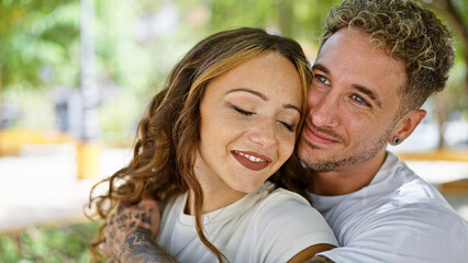 Fototapeta premium Affectionate man and woman embracing happily in a sunny park setting, displaying intimacy and a strong bond