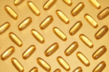 Photo was shot from above view for nutrition supplements advertisement. Medicine background with several fish oil capsules evenly arranged on golden color background