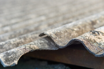 The corrugated asbestos roof has aged and deteriorated, its surface faded by the weather. Broken...