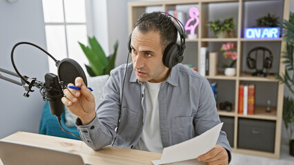 Handsome man with headphones in radio studio holding script on-air