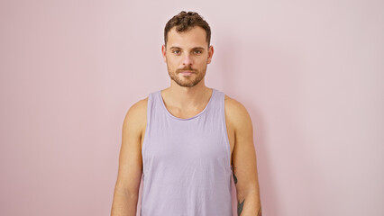 Handsome young hispanic man with a beard standing against an isolated pink wall in a portrait pose.