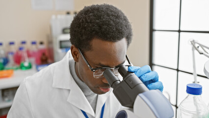 African american man conducting research using a microscope in a science laboratory