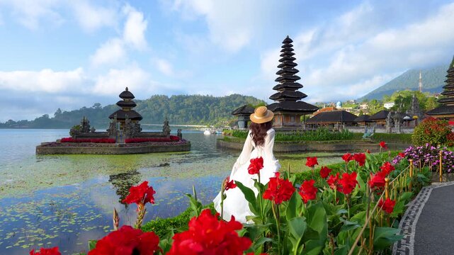 4k slow motion video.Young female tourist at Pura ulun danu bratan temple in Bali, Indonesia.In the morning and the beautiful sky
