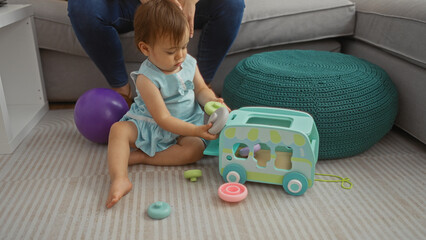 Toddler playing with toys on the floor in a living room while being watched by a woman nearby, showcasing family bonding and indoor playtime.