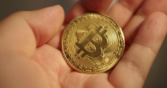 Flipping using her fingers, an individual is holding on to a piece of gold Bitcoin.