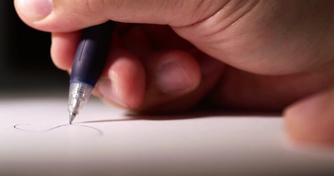 Blurry close-up of an individual's hand while scribbling some notes using a pen on a clean white sheet of paper.