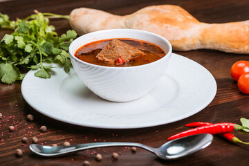 spicy soup with kharcho with beef, tomatoes and vegetables on a wooden surface. Georgian soup. Turkish soup