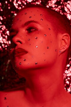 Vertical closeup portrait of young woman with bold makeup over red filter