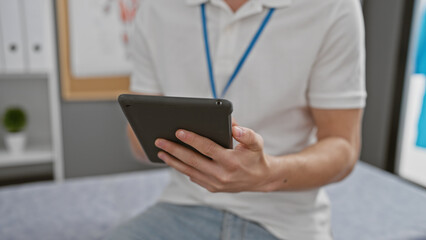 A professional man in a clinic uses a tablet, epitomizing modern healthcare technology in an indoor setting.