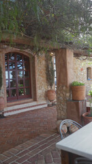 A tranquil mediterranean villa entrance with terracotta tiles and a lush green overhang.