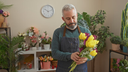 Handsome man arranging colorful flowers in a cozy indoor florist shop