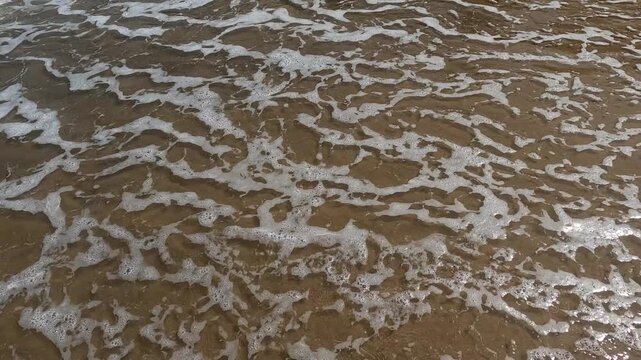 Suave oleaje y espuma de mar sobre la fina arena de la playa de Tazones, litoral del mar Cant&aacute;brico, norte de Espa&ntilde;a