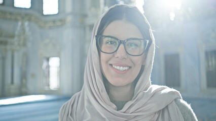 Smiling woman with glasses wearing headscarf inside ornate istanbul mosque radiates beauty and...