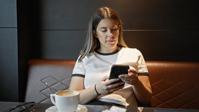 A young adult woman engaged with her smartphone in a modern cafe setting, exuding a casual yet focused ambiance.