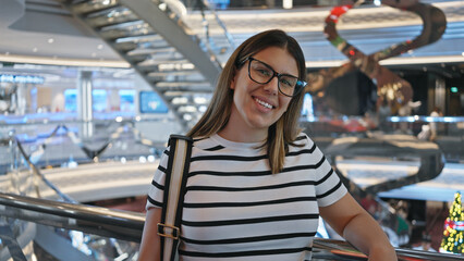 A smiling young woman on a modern luxury cruise with a spacious interior, enjoying her vacation travel.