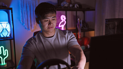 A young asian man enjoys sim racing in a home gaming setup at night, portraying technology and leisure.