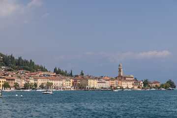 Naklejka premium Salo charming promenade on Lake Garda, featuring bustling bar and scenic views, captures the essence of a vibrant Italian lakeside town