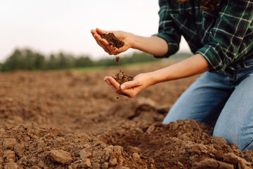 Female farmer hands holding black soil in their hands. Fertile land. garden field ground fertile concept.