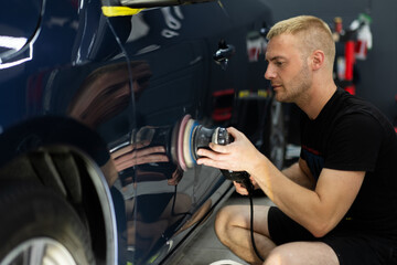 A car care specialist uses a polishing machine, bringing the surface to a shine