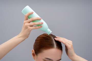 Naklejka premium Young woman using a new shampoo and looking happy