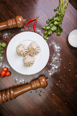 khinkali with meat, mushrooms and potatoes, herbs on a white plate