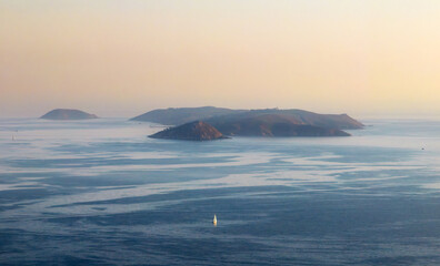 A solitary boat sailing in the Ría de Pontevedra in Galicia at dusk, with the serene Ons Islands in the background.