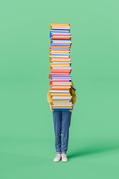 Woman Holding a Tall Stack of Books on Green Background