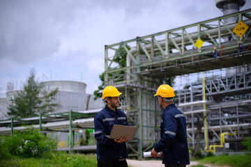 Blue collar workers are working at refinery factory.