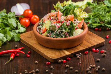 Georgian Tbilisi style salad with tomatoes, cucumbers and meat on a wooden table