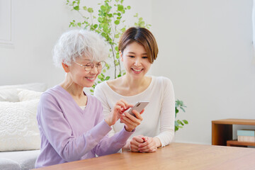 スマートフォンを使う母親と娘　リビングルーム