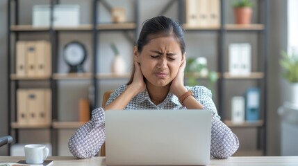A woman in discomfort, holding her neck with a strained expression while sitting in front of a laptop, highlighting the effects of long screen time.